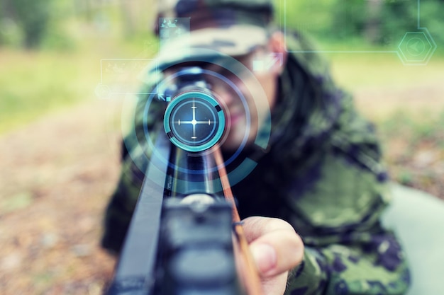 caça, guerra, exército, tecnologia e conceito de pessoas - close-up de jovem soldado ou atirador segurando arma com projeção de tela virtual e mirando na floresta