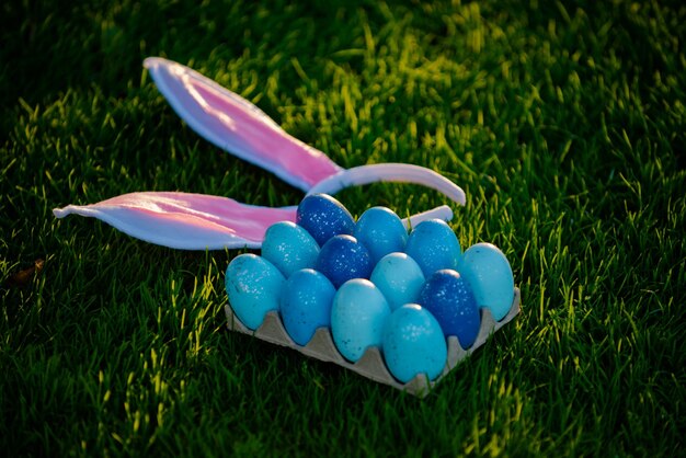 Caça ovos de páscoa ovos de páscoa e orelhas de coelho no conceito de férias de primavera de fundo de grama verde