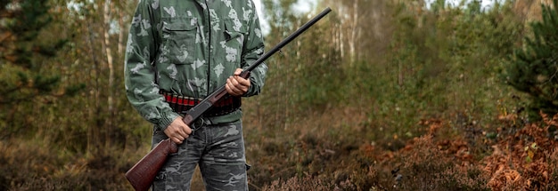 Caçador camuflado com uma arma durante a caça