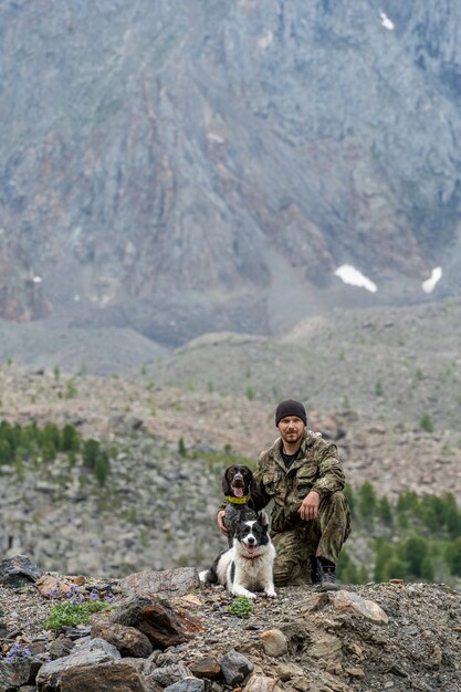 Caçador com dois cães sentado no fundo de uma montanha