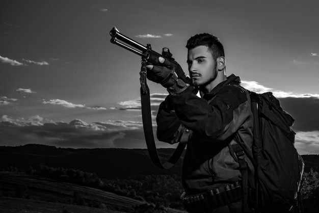 Caçador com espingarda no equipamento de caça para venda caçador mirando rifle na floresta montanha hu