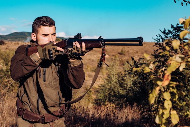 Caçador com rifle poderoso com mira caçador de animais com espingarda na pista de caça