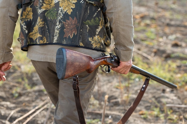 Caçador de homem maduro com arma enquanto caminhava no campo