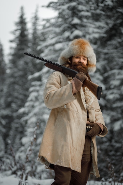 Caçador em roupas vintage com arma foge pela floresta