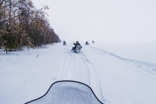 Foto caçadores em motos de neve andam na floresta de inverno