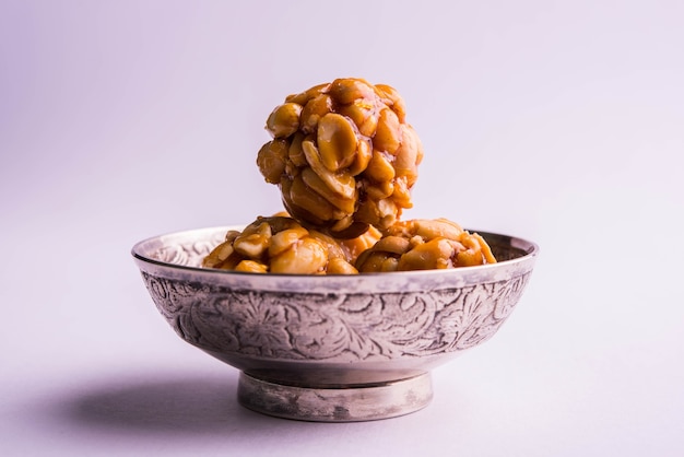 Cacahuete o maní dulce y saludable y Jaggery Laddoo, servido en una placa de latón aislada sobre fondo blanco. enfoque selectivo