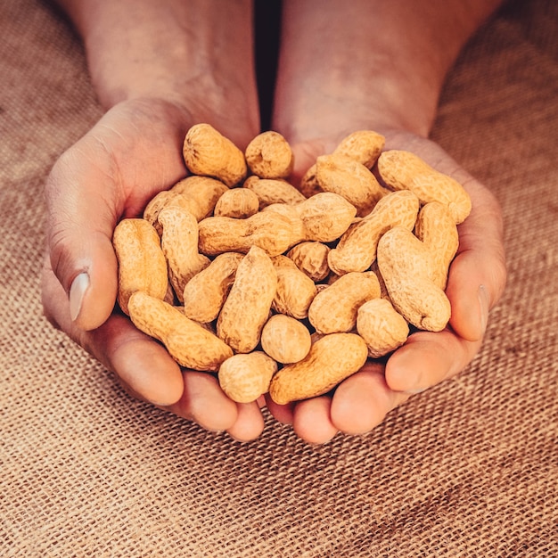 Cacahuetes con cáscara en manos masculinas fuertes