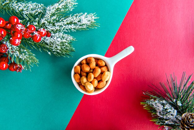 Cacahuetes en la mesa de Navidad con fondo verde y rojo