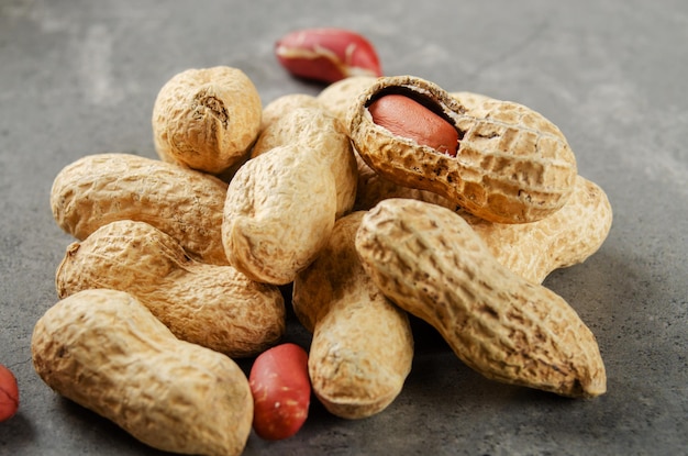 Foto cacahuetes orgánicos maduros con cáscara sobre mesa de piedra. concepto de alimentación saludable