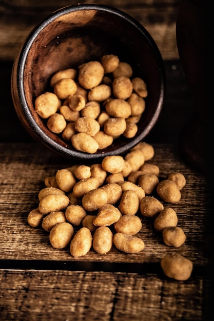 Cacahuetes salados rebozados en bol marrón sobre fondo oscuro, ideal para acompañar la cerveza.