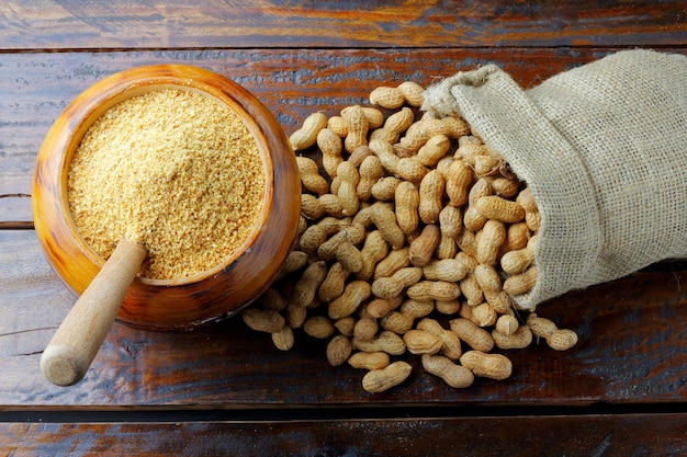 Cacahuetes triturados y molidos en el cuenco de madera formando un ingrediente de harina para la mantequilla y pasta de cacahuete y la comida orgánica pacoca brasileña