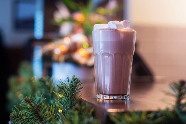 Cacao con malvaviscos en un vaso transparente en una cafetería en el fondo de la decoración de Año Nuevo.