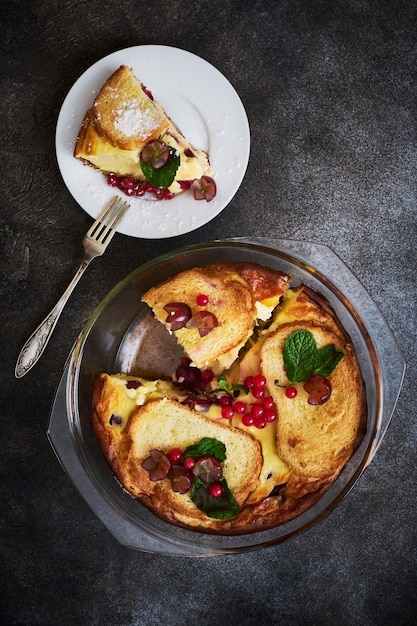 Caçarola de coalhada deliciosa com groselhas frescas e uvas e croutons em uma assadeira de vidro