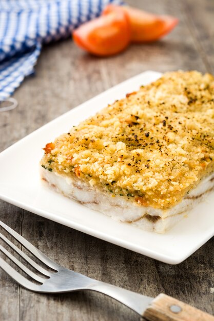 Foto caçarola de peixe branco com queijo em madeira.