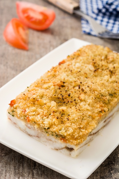 Caçarola de peixe branco com queijo no fundo de madeira.