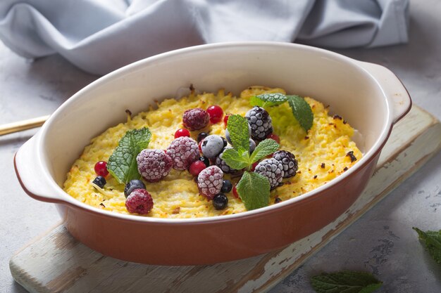 Caçarola de queijo cottage assada com frutas frescas na mesa da cozinha.