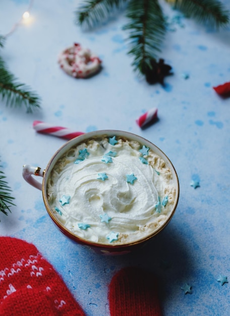 Cacau caseiro ou chocolate quente com doces de creme de abeto e luvas vermelhas em fundo de concreto azul Natal ou ano novo bebida aconchegante decoração de casa foco seletivo