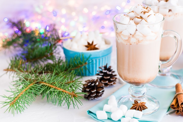 Cacau quente com marshmallow e canela em pó em copos em decorações de natal