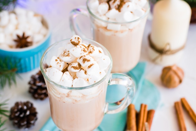 Cacau quente com marshmallow e canela em pó em copos na mesa