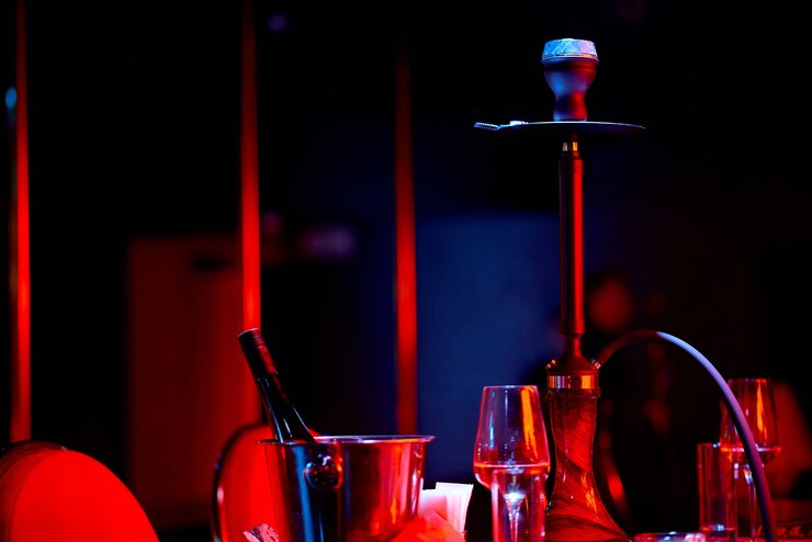Cachimbo de água clássico na mesa em luz azul e vermelha com copos e um balde com vinho. Foto de alta qualidade