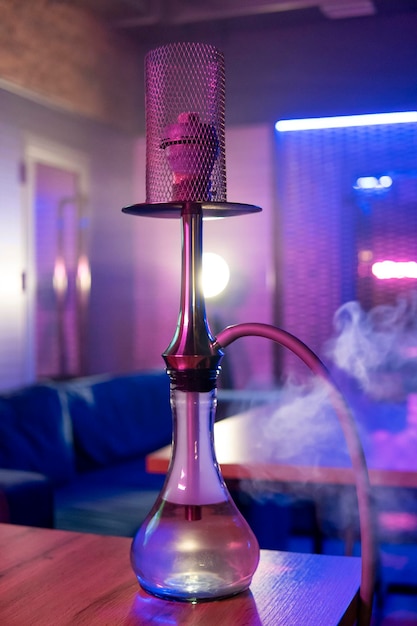 Cachimbo de água em cima da mesa com luz de néon rosa azul