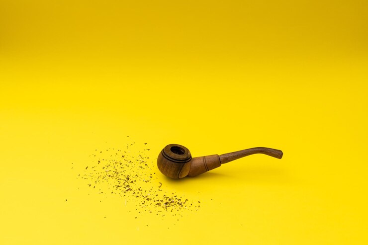 Foto cachimbo de madeira com tabaco em um fundo amarelo, o fumo prejudica