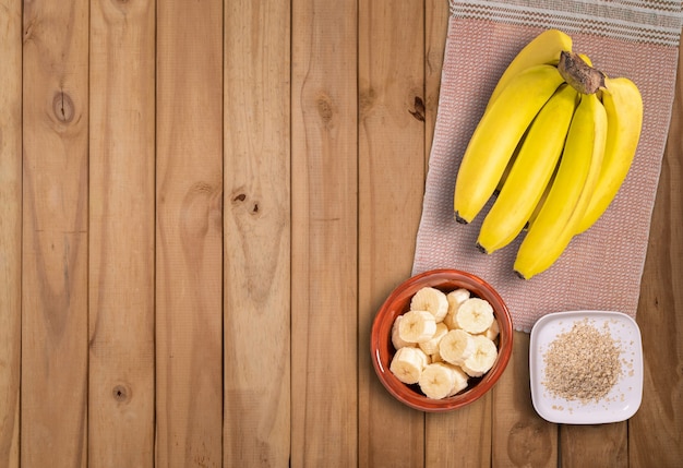 Cacho de bananas e bananas fatiadas na mesa de madeira