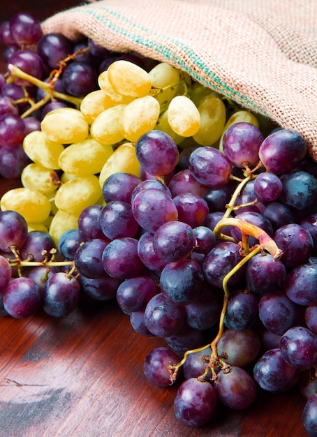 Cacho de uvas pretas e verdes na superfície de madeira