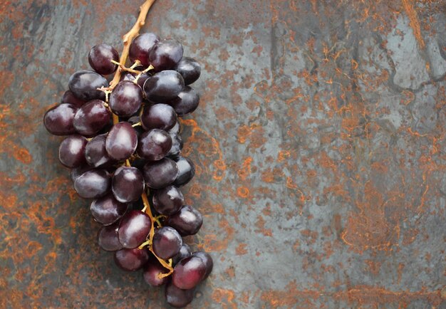 Cacho de uvas preto sobre fundo metálico com ferrugem