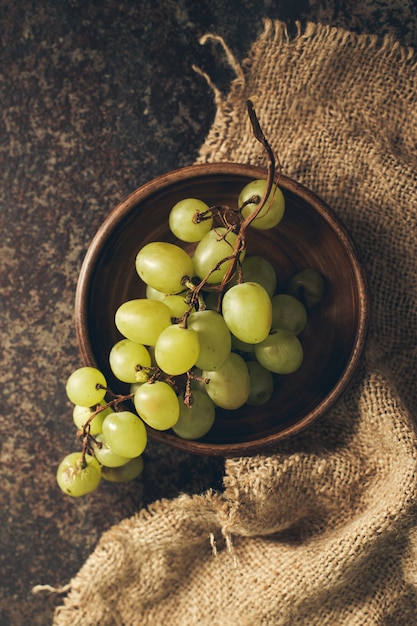 Cacho de uvas verdes em um fundo escuro.