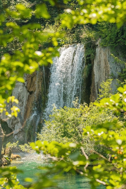 Cachoeira cai da rocha em água turquesa à luz do sol