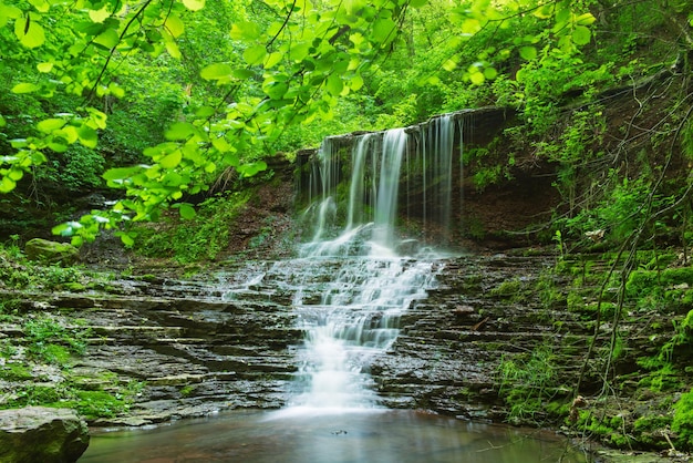 Cachoeira da floresta tropical bela montanha com água corrente e rochas, longa exposição. Viagem sazonal natural, plano de fundo ao ar livre em estilo vintage moderno