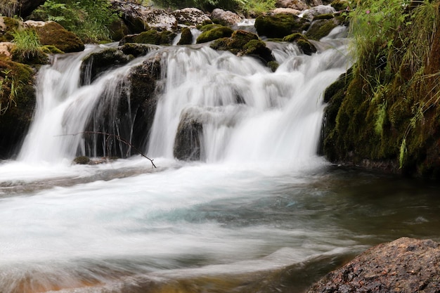 Cachoeira que flui através de rochas cobertas de musgo