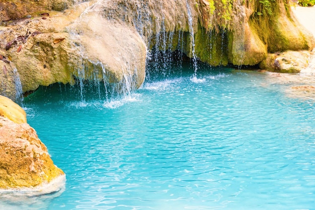 Cachoeira tropical com lago azul esmeralda e rochas na floresta da selva