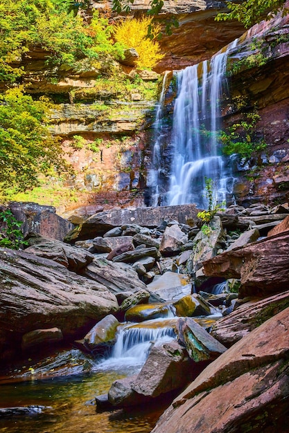 Cachoeiras grandes e pequenas caindo sobre as bordas do penhasco através de pedras rochosas com folhagem de outono