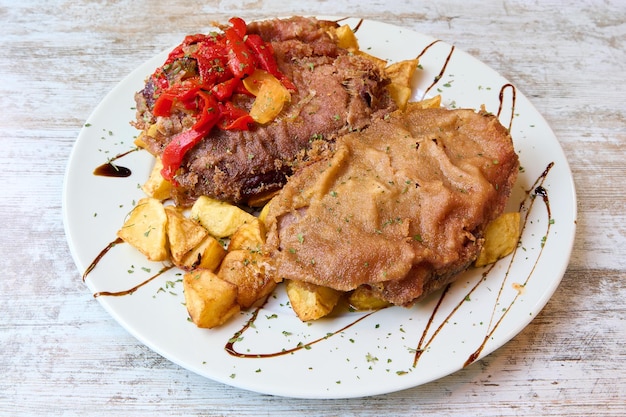 Foto cachopo asturiano com batatas fritas e pimentos assados