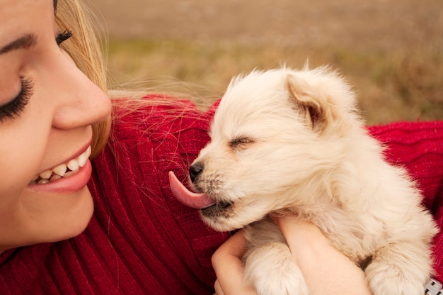 Cachorrinho enfiando a língua para fora e a garota sorridente segurando-o.