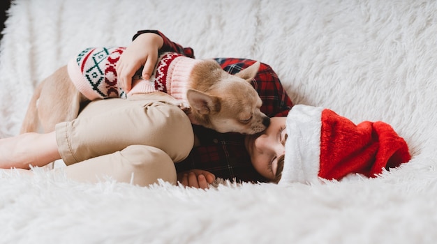 Cachorro com suéter lambendo criança rindo no natal