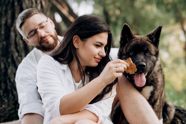 Cachorro grande para passear com um cara e uma garota na pradaria verde