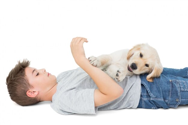 Cachorro jugando en chico acostado sobre fondo blanco