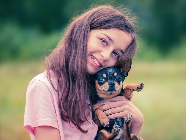 Foto cachorro nos braços de uma adolescente. chihuahua preto.