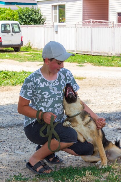 Un cachorro de perro pastor alemán juega con un adolescente en una calle rural en un día de verano