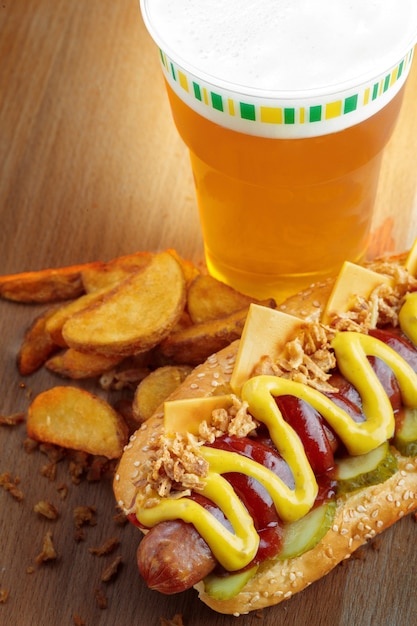Cachorro-quente com mostarda amarela e ketchup na tábua de madeira