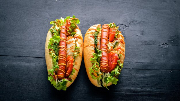 Cachorro-quente com mostarda de salsicha grelhada e ketchup cebolas e verduras em fundo de madeira Vista superior Espaço livre