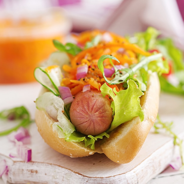 Foto cachorro-quente com pepino, cenoura, tomate e alface em fundo de madeira. menu de fast food.