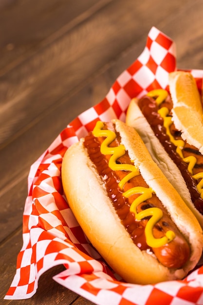 Cachorro-quente grelhado com mostarda e ketchup na mesa com chope.