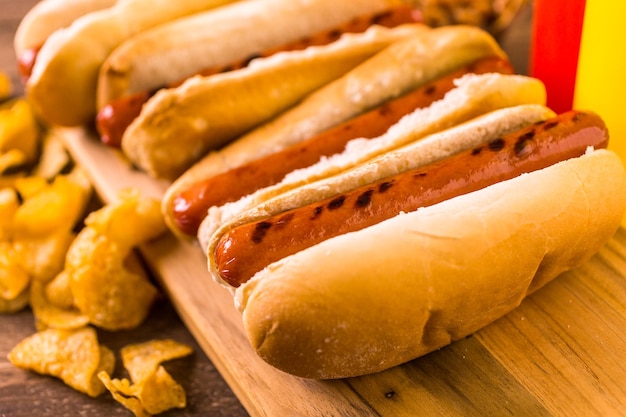 Cachorro-quente grelhado com pãezinhos de cachorro-quente branco com batatas fritas e feijão cozido ao lado.