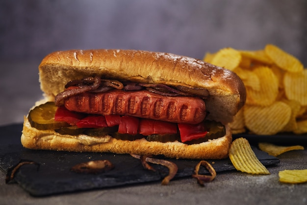 Cachorro-quente - salsicha quente aninhada em um pão com pepinos, pimenta e cebola.