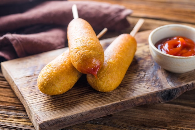 Cachorros de milho ou salsicha em rolo com ketchup cena de mesa de vista superior sobre um fundo de madeira