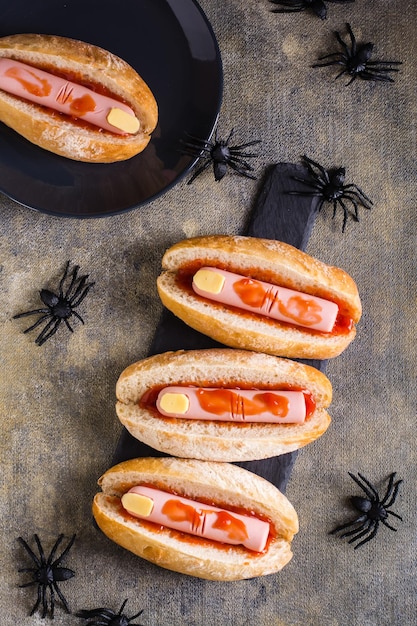 Cachorros-quentes de salsicha e queijo em ketchup em pães na ardósia Receita de Halloween Top e vertical